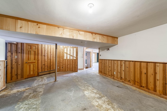 basement featuring a baseboard heating unit and wooden walls