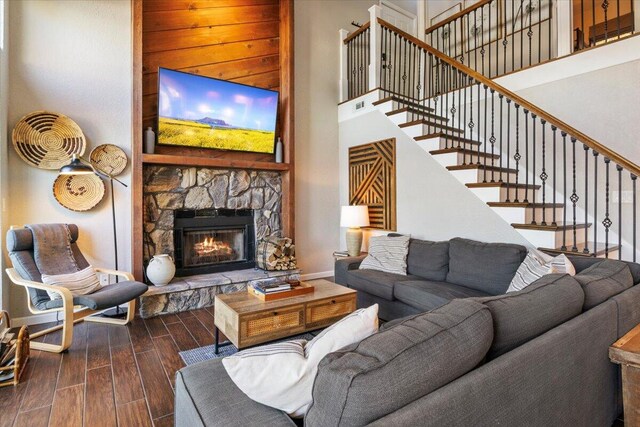 living room featuring a stone fireplace, dark hardwood / wood-style flooring, and a high ceiling