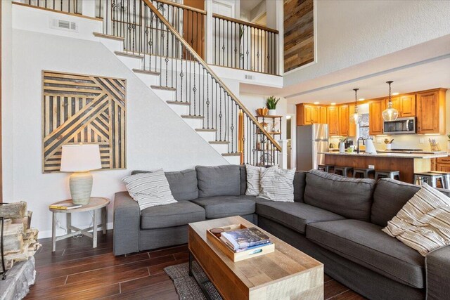 living room featuring a towering ceiling, dark hardwood / wood-style floors, and sink