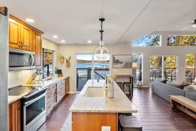 kitchen featuring stainless steel appliances, a kitchen island with sink, sink, a water view, and a breakfast bar area