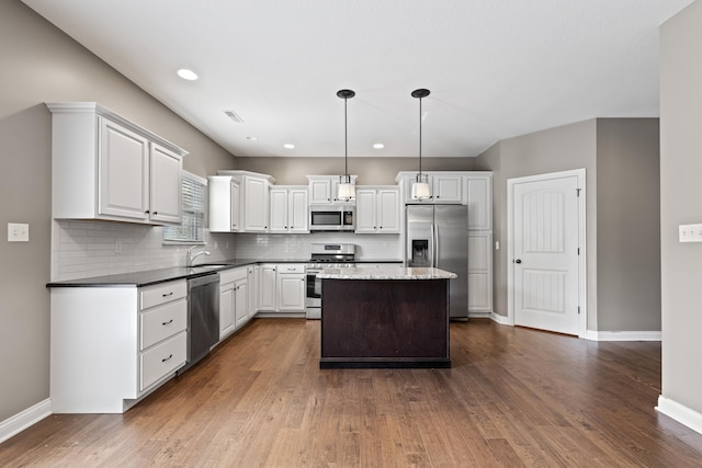 kitchen featuring white cabinets, stainless steel appliances, hanging light fixtures, and dark hardwood / wood-style flooring