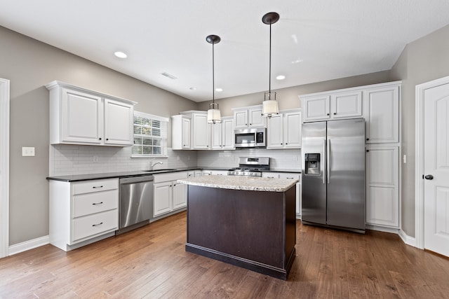 kitchen with hanging light fixtures, dark hardwood / wood-style floors, white cabinets, and appliances with stainless steel finishes