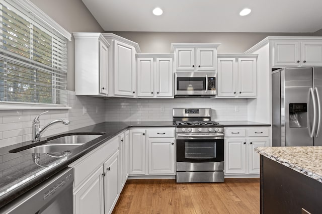 kitchen featuring white cabinetry, sink, light hardwood / wood-style flooring, and appliances with stainless steel finishes