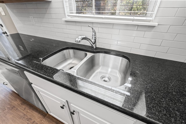 room details with dark stone counters, dark hardwood / wood-style floors, decorative backsplash, sink, and white cabinets