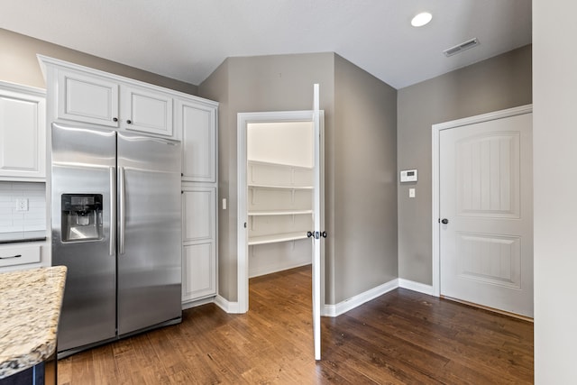 kitchen with stainless steel fridge, white cabinetry, backsplash, and dark hardwood / wood-style flooring