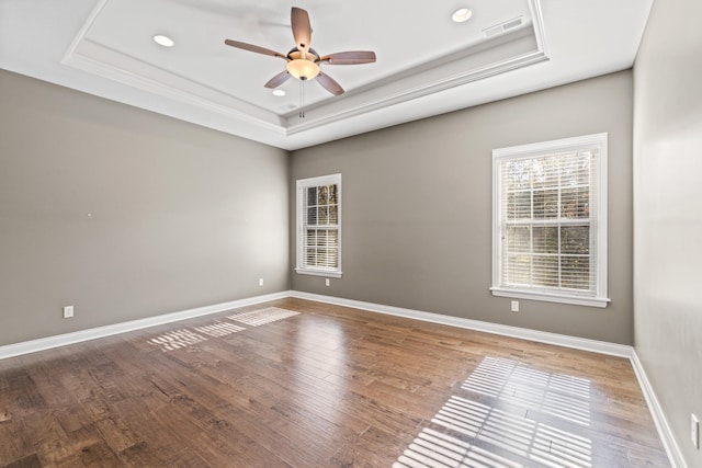 unfurnished room with a tray ceiling and wood-type flooring