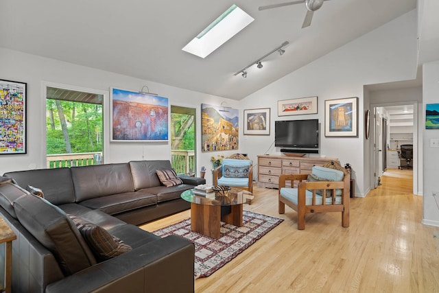 living room featuring lofted ceiling with skylight, track lighting, light hardwood / wood-style floors, and ceiling fan