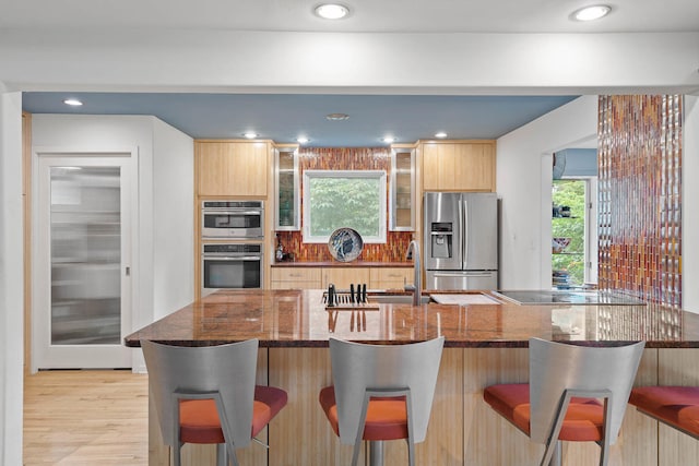 kitchen with a kitchen breakfast bar, kitchen peninsula, stainless steel appliances, and plenty of natural light