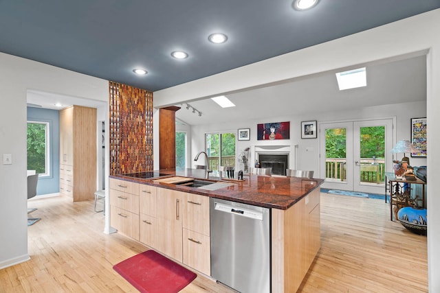 kitchen featuring light brown cabinets, a kitchen island with sink, stainless steel dishwasher, light hardwood / wood-style floors, and french doors