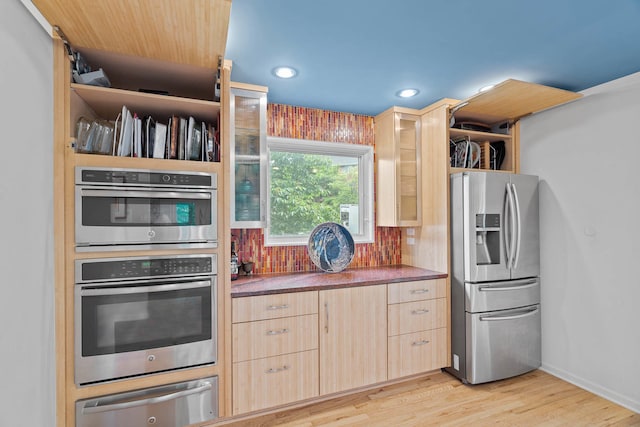 kitchen featuring light brown cabinets, light hardwood / wood-style flooring, stainless steel appliances, and backsplash