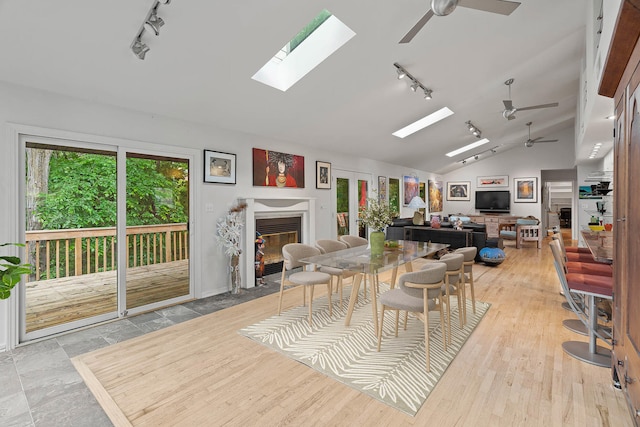 dining space with light hardwood / wood-style flooring, lofted ceiling with skylight, ceiling fan, and rail lighting