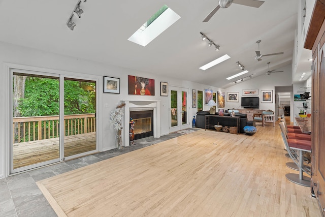 living room featuring lofted ceiling with skylight, track lighting, and plenty of natural light