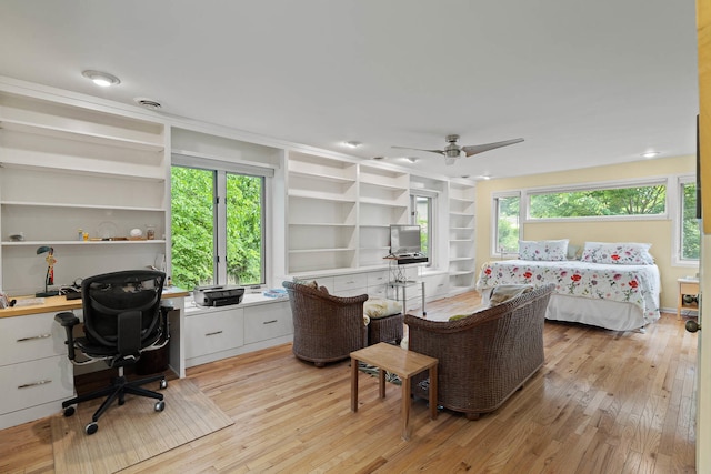 home office featuring light hardwood / wood-style flooring, ceiling fan, built in shelves, and a wealth of natural light