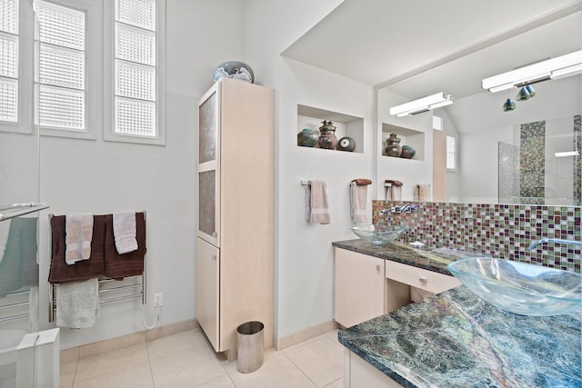 bathroom with decorative backsplash, tile patterned flooring, vaulted ceiling, and a wealth of natural light