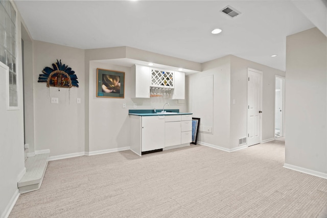 bar featuring light carpet, white cabinetry, and sink