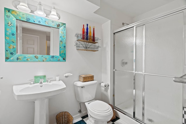 bathroom featuring a shower with shower door and toilet