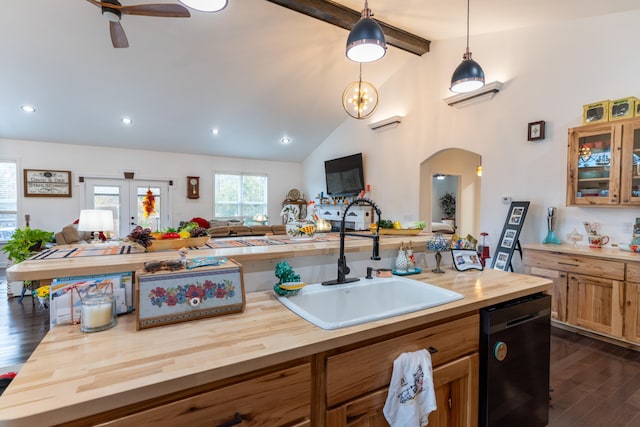 kitchen with lofted ceiling with beams, hanging light fixtures, sink, and wooden counters