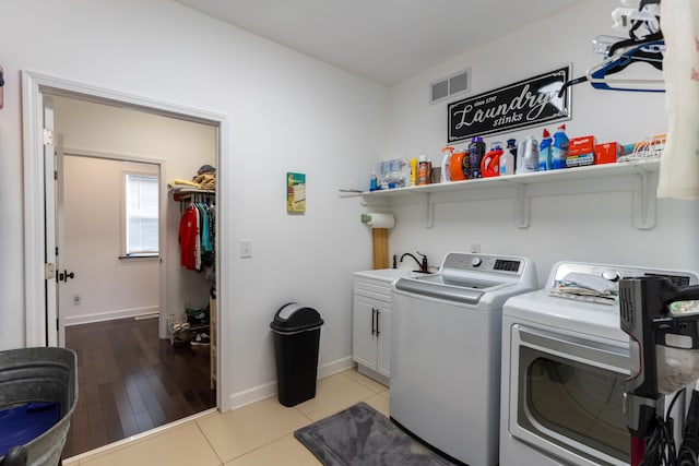 clothes washing area with cabinets, separate washer and dryer, sink, and light tile patterned floors