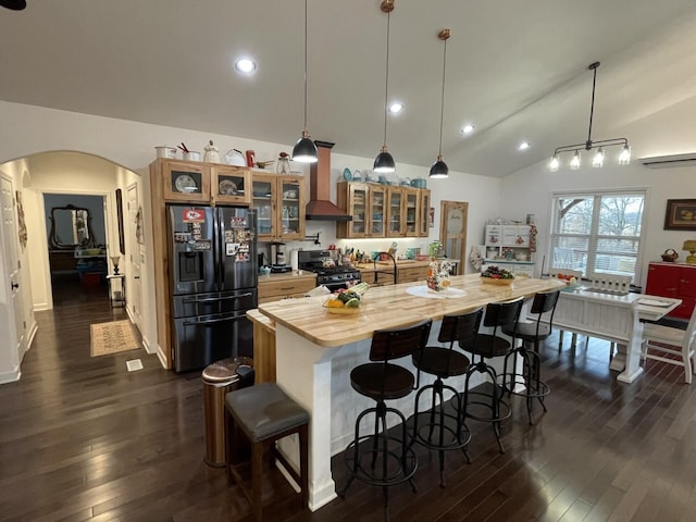 kitchen with stainless steel gas range, custom exhaust hood, black fridge, a center island, and hanging light fixtures