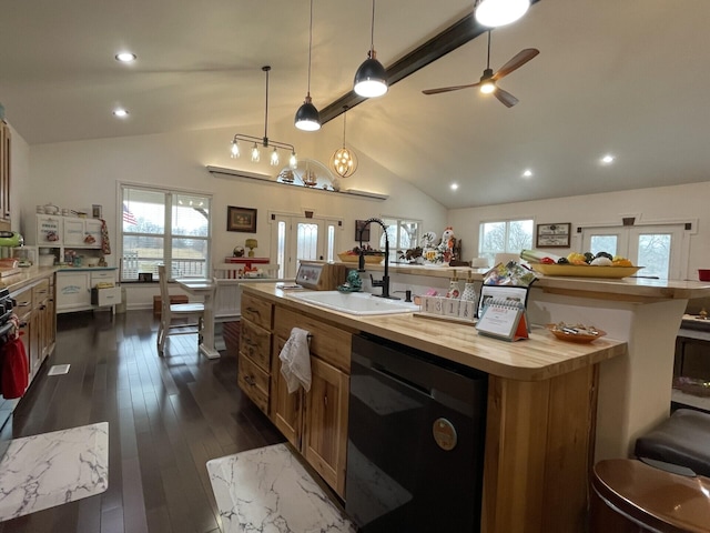 kitchen with pendant lighting, sink, butcher block counters, black dishwasher, and a center island with sink