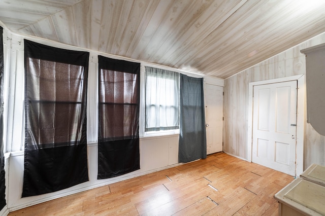 spare room featuring light wood-type flooring, wood walls, vaulted ceiling, and wooden ceiling