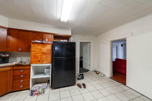 kitchen featuring ornamental molding, decorative backsplash, black appliances, and light tile patterned floors