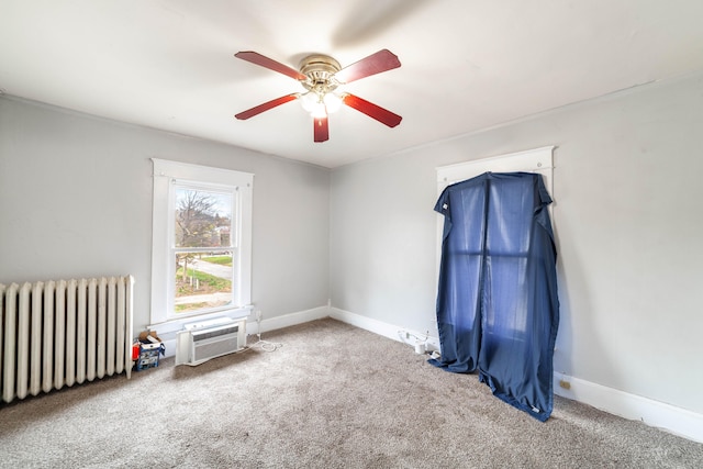 spare room featuring radiator, a wall unit AC, ceiling fan, and carpet floors