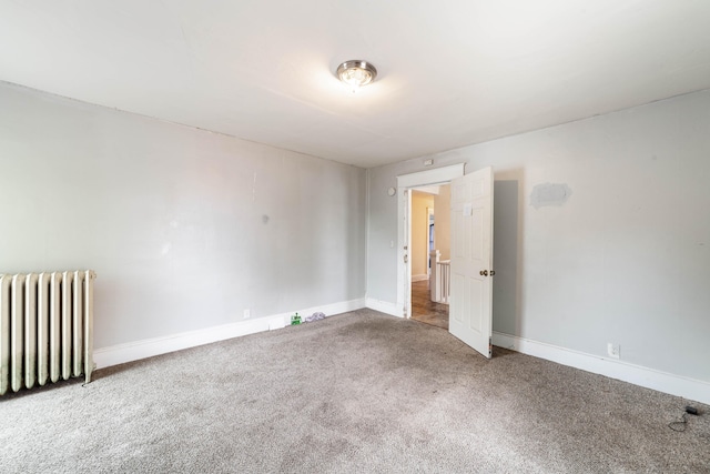 empty room featuring radiator heating unit and carpet floors