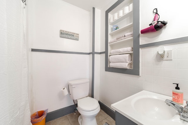 bathroom with walk in shower, vanity, tile patterned floors, toilet, and tile walls