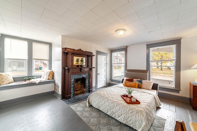 bedroom with dark hardwood / wood-style floors, multiple windows, and a high end fireplace