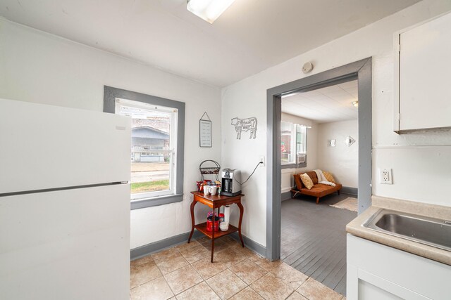 kitchen featuring white cabinetry, a healthy amount of sunlight, white fridge, and light tile patterned flooring