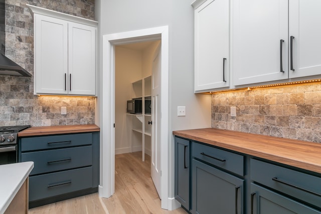 kitchen featuring butcher block countertops and white cabinetry