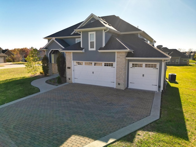 view of front facade featuring a front yard, a garage, and central AC unit