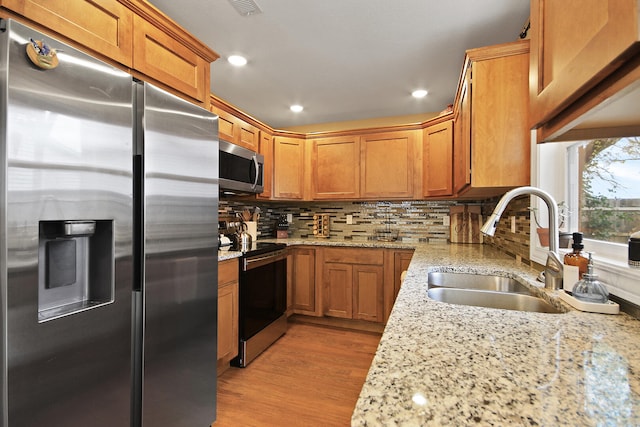 kitchen featuring sink, light stone counters, and stainless steel appliances