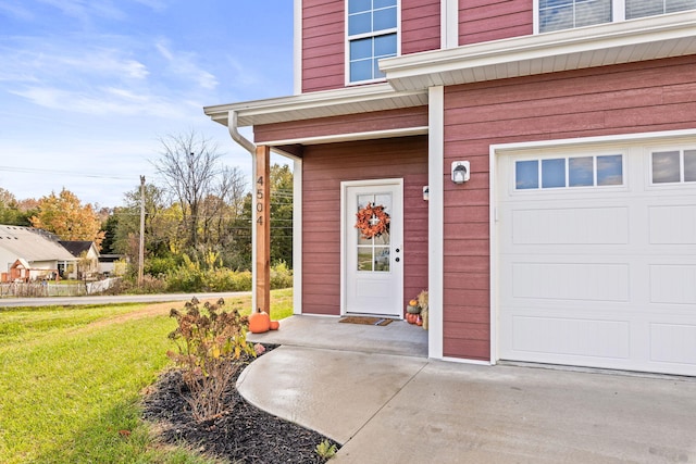 view of exterior entry with a lawn and a garage