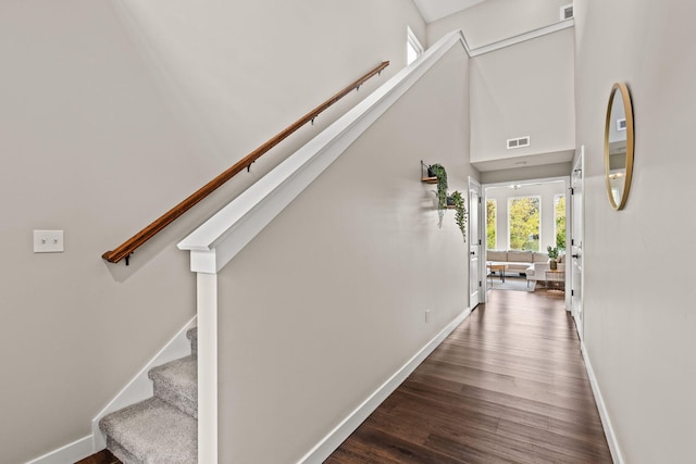 hallway with dark wood-type flooring and a high ceiling