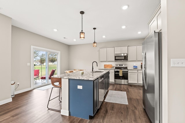 kitchen featuring a kitchen island with sink, appliances with stainless steel finishes, dark hardwood / wood-style floors, and decorative light fixtures