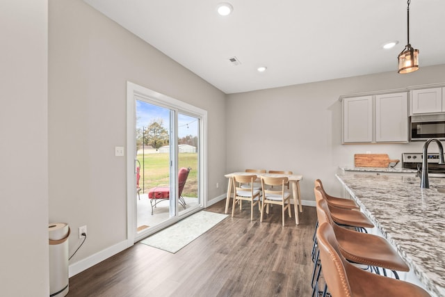 kitchen with white cabinetry, dark wood-type flooring, decorative light fixtures, and light stone countertops