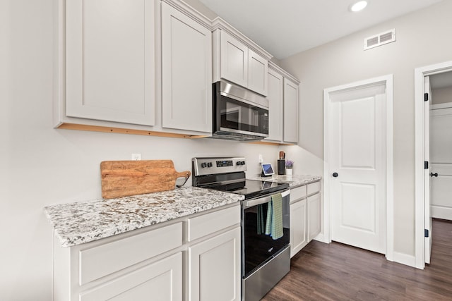 kitchen featuring dark hardwood / wood-style flooring, white cabinetry, appliances with stainless steel finishes, and light stone countertops