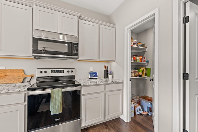 kitchen with white cabinets, stainless steel appliances, dark wood-type flooring, and light stone countertops