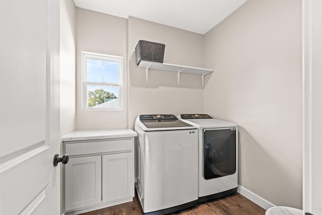 clothes washing area featuring cabinets, dark hardwood / wood-style flooring, and washer and clothes dryer