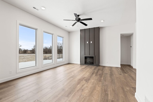 unfurnished living room with a fireplace, ceiling fan, and light wood-type flooring