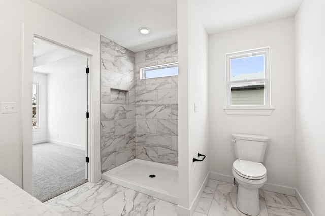 bathroom with a tile shower and toilet