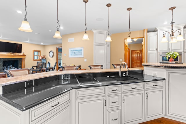 kitchen with light hardwood / wood-style floors, white cabinetry, sink, and pendant lighting