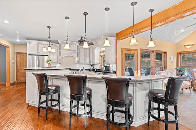 kitchen with stainless steel refrigerator, hardwood / wood-style flooring, a breakfast bar, and pendant lighting