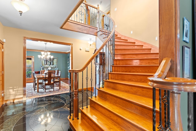 stairs with an inviting chandelier and ornamental molding