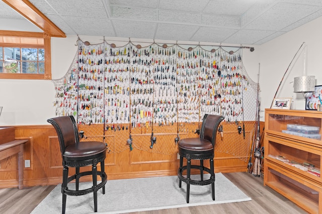 interior space featuring a paneled ceiling, hardwood / wood-style flooring, and wood walls