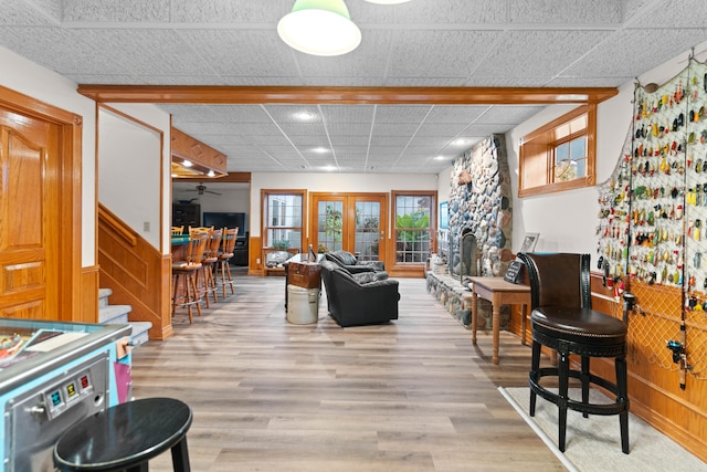 living room featuring light hardwood / wood-style floors, a drop ceiling, a fireplace, and ceiling fan