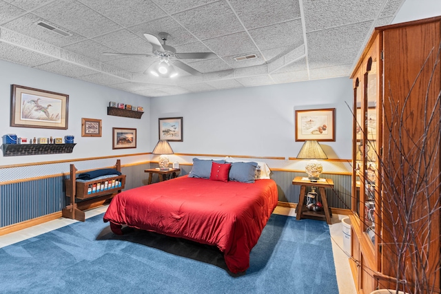 carpeted bedroom with a paneled ceiling and ceiling fan