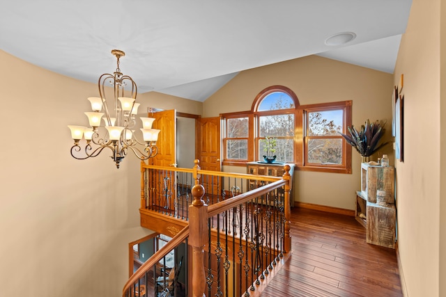 hallway featuring a chandelier, wood-type flooring, and vaulted ceiling